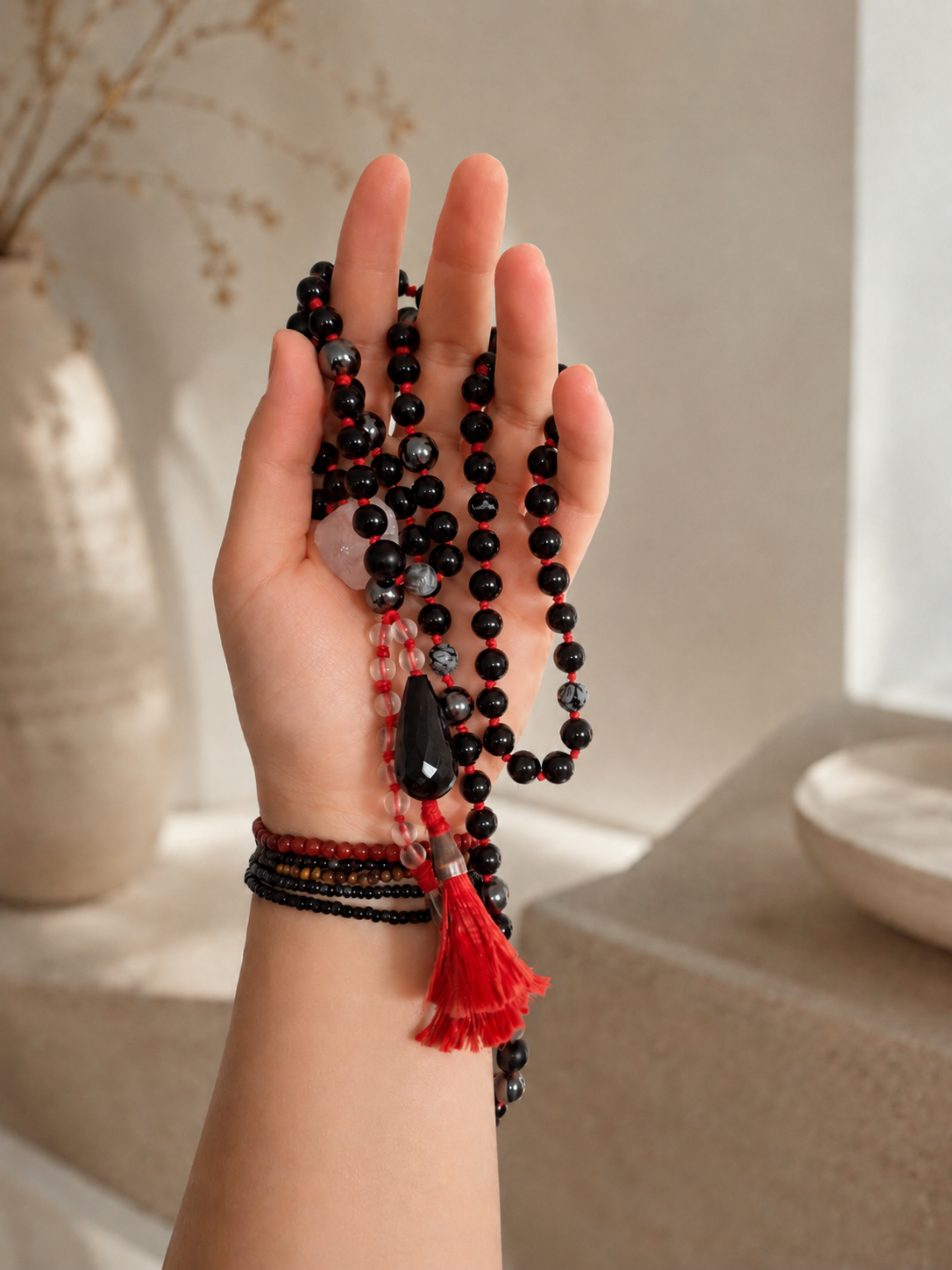 mala in the hand, black gemstones and red tassels